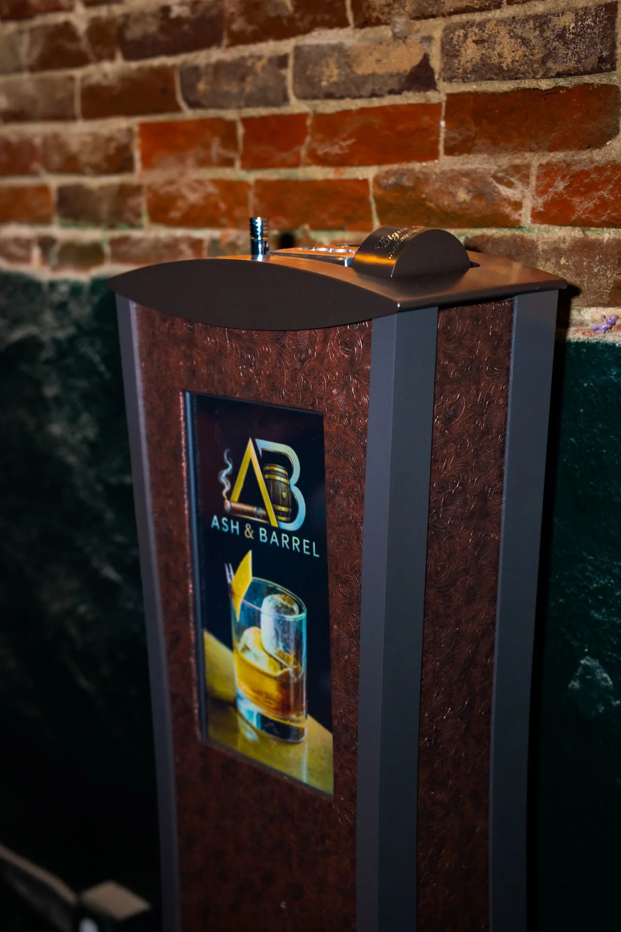 Ash & Barrel branded cigar ash tower against an exposed brick wall