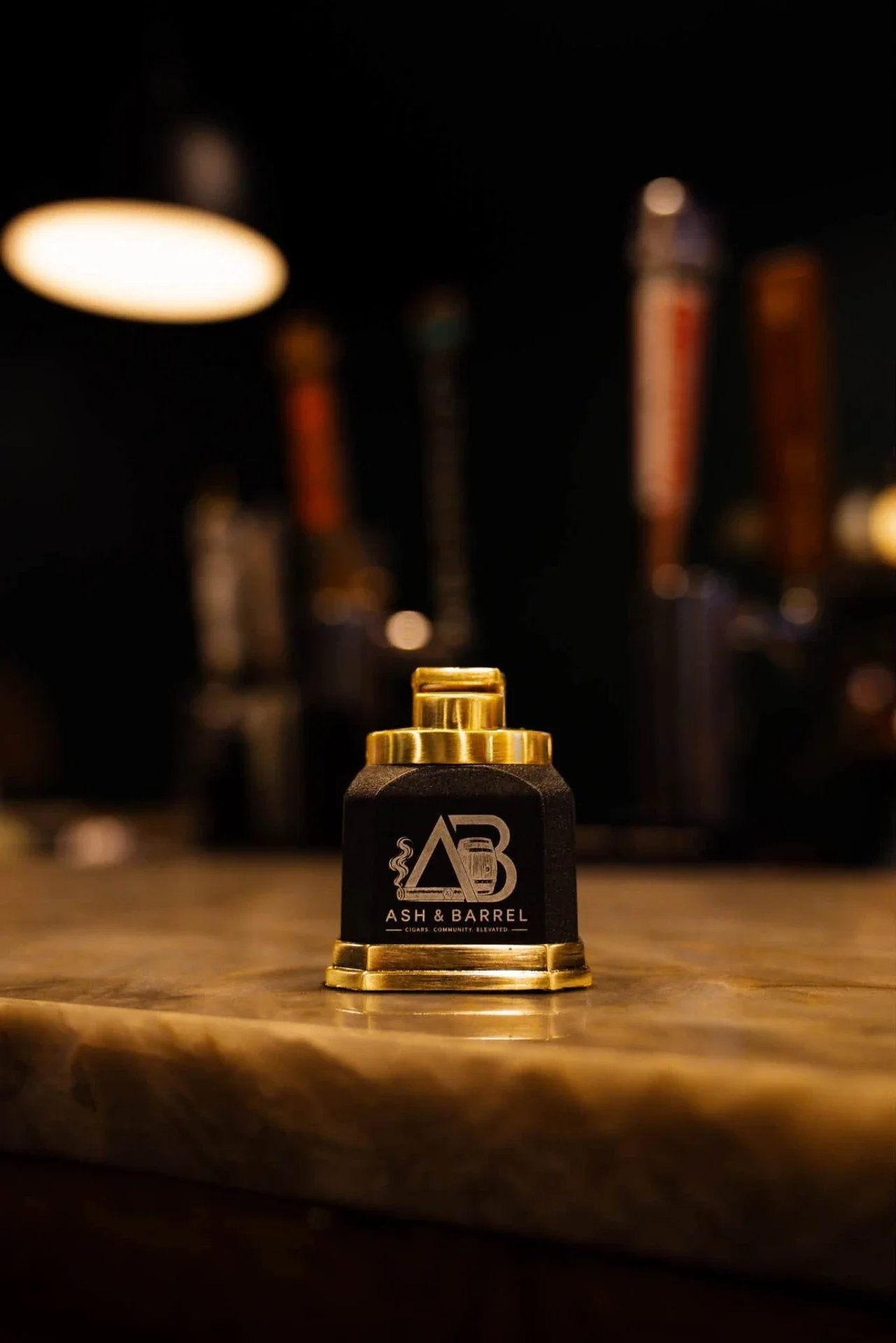 Ash & Barrel branded gold table lighter on the bar