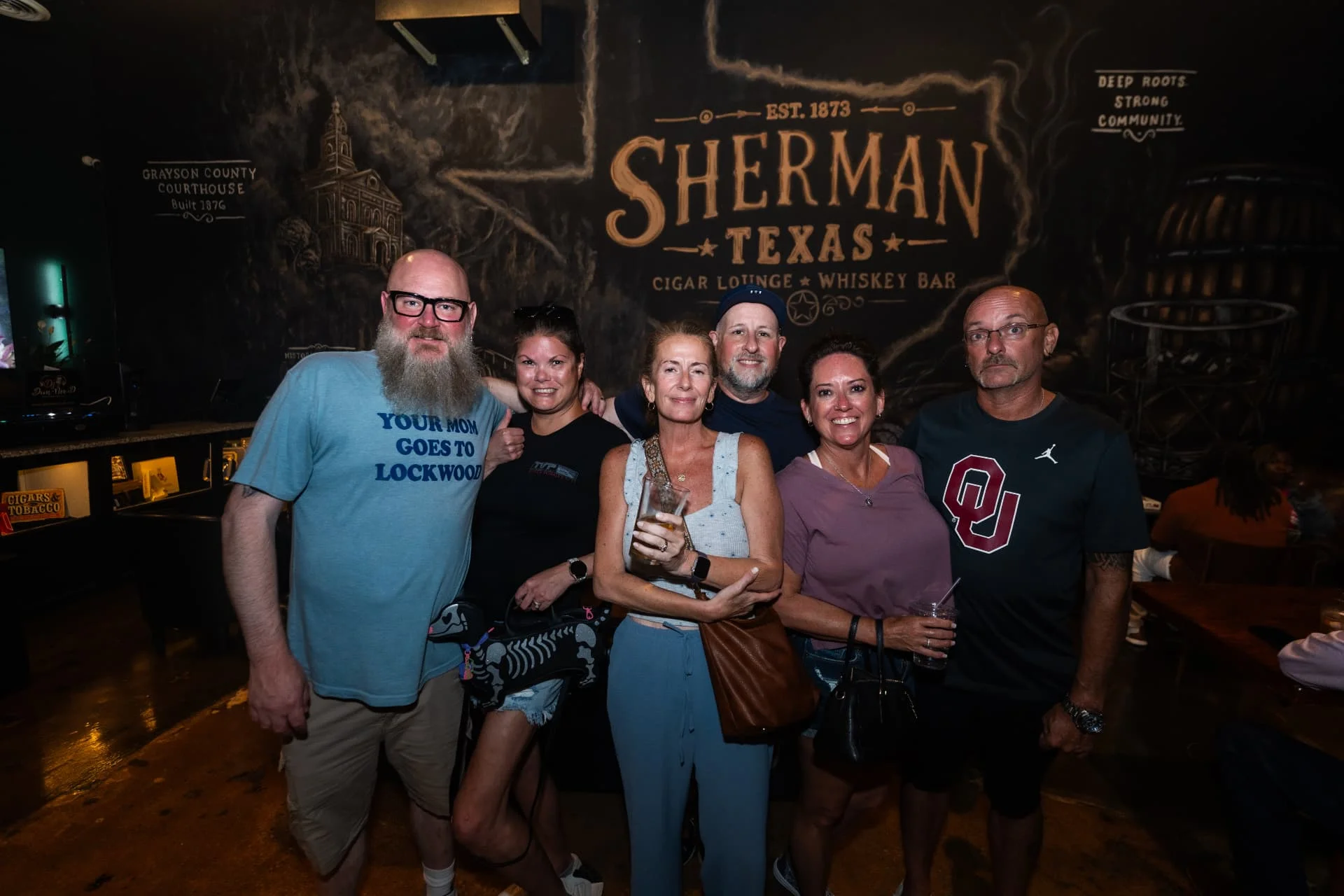 Friends gathered in front of the Sherman mural at Ash & Barrel