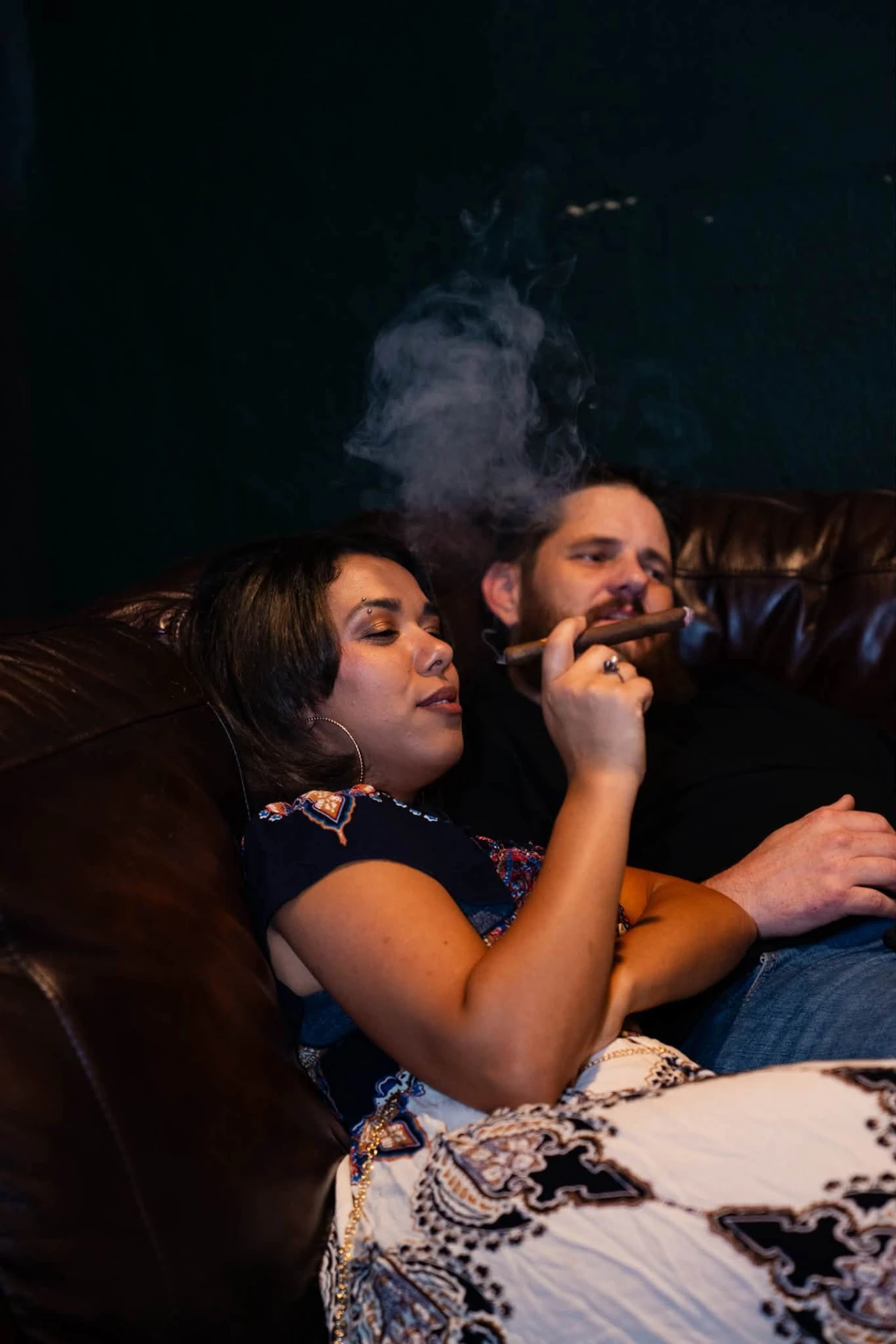 Couple relaxing on a leather couch with cigars