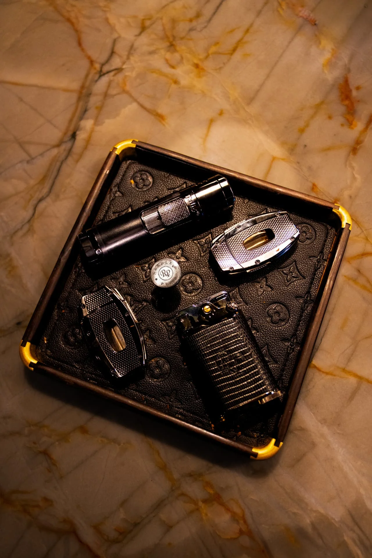Cigar cutters, torch lighters and punch on a leather tray at Ash & Barrel